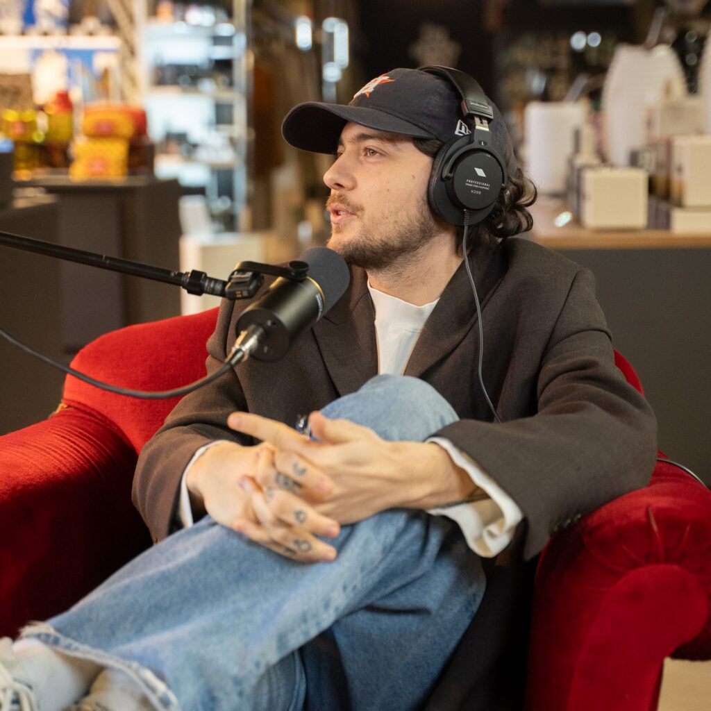 Un ospite del podcast con cuffie, seduto su una poltrona rossa in velluto
