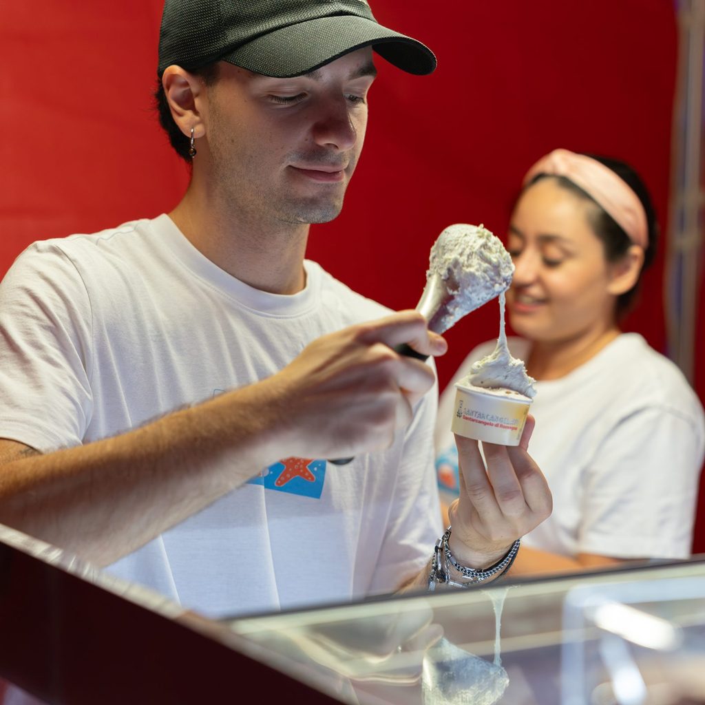Uomo con cappellino che serve gelato allo stand con una collega sorridente