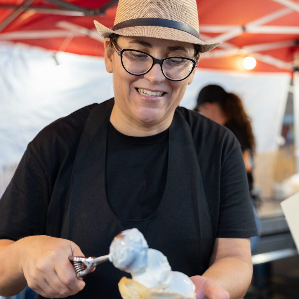 Gelatiera con cappello di paglia che prepara una brioche col gelato allo stand Santarcangelato