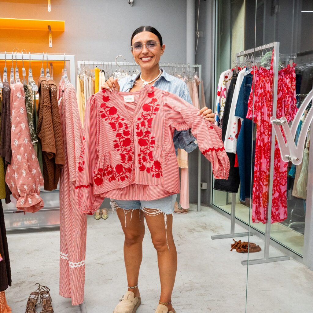 Ragazza in un negozio di abbigliamento mostra una camicia rosa a fiori